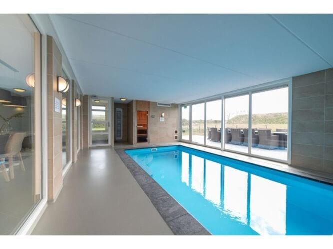 een groot zwembad in een gebouw met blauw water bij Luxury holiday home in Colijnsplaat in Colijnsplaat
