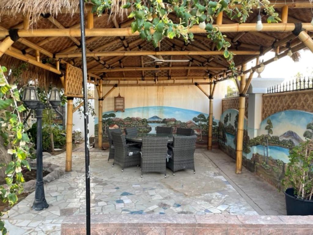 eine Terrasse mit einem Tisch und Stühlen unter einer Pergola in der Unterkunft Alhosani property in Abu Dhabi
