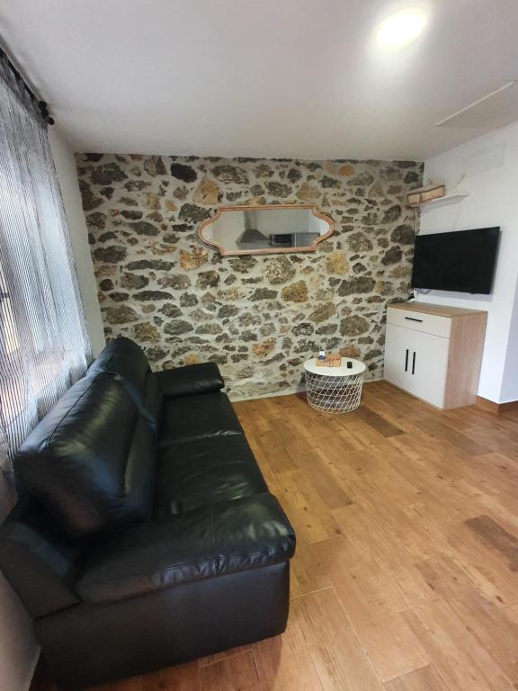 uma sala de estar com um sofá de couro e uma parede de pedra em PORTILLO - LA COLINA em Arnuero