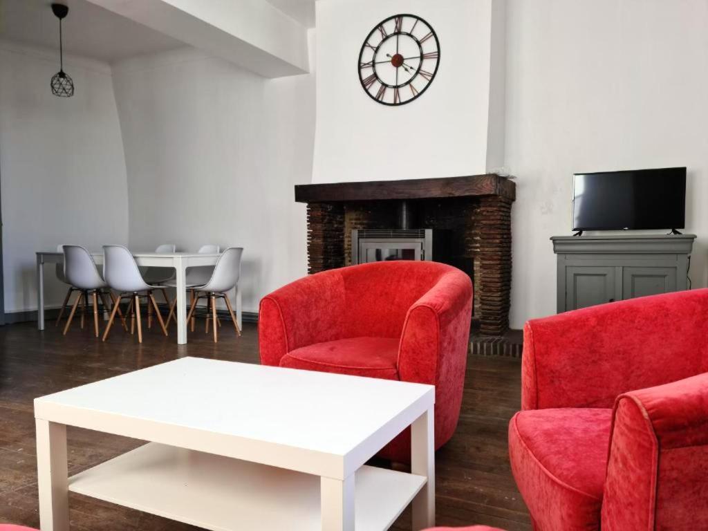 ein Wohnzimmer mit roten Stühlen, einem Tisch und einer Uhr in der Unterkunft Appartement de 3 chambres avec wifi a Beaugency in Beaugency