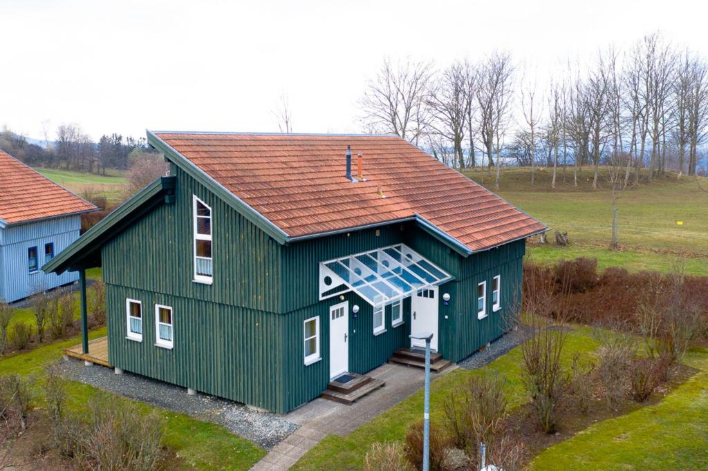 una casa verde con un panel solar. en Ferienhaus Nr 13B1, Feriendorf Hagbügerl, Bayr Wald, en Waldmünchen