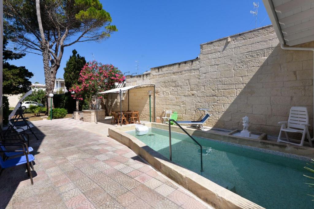 托里德奧索的住宿－Dimora Villa Orietta - Torre dell'Orso，一座石头建筑旁的游泳池