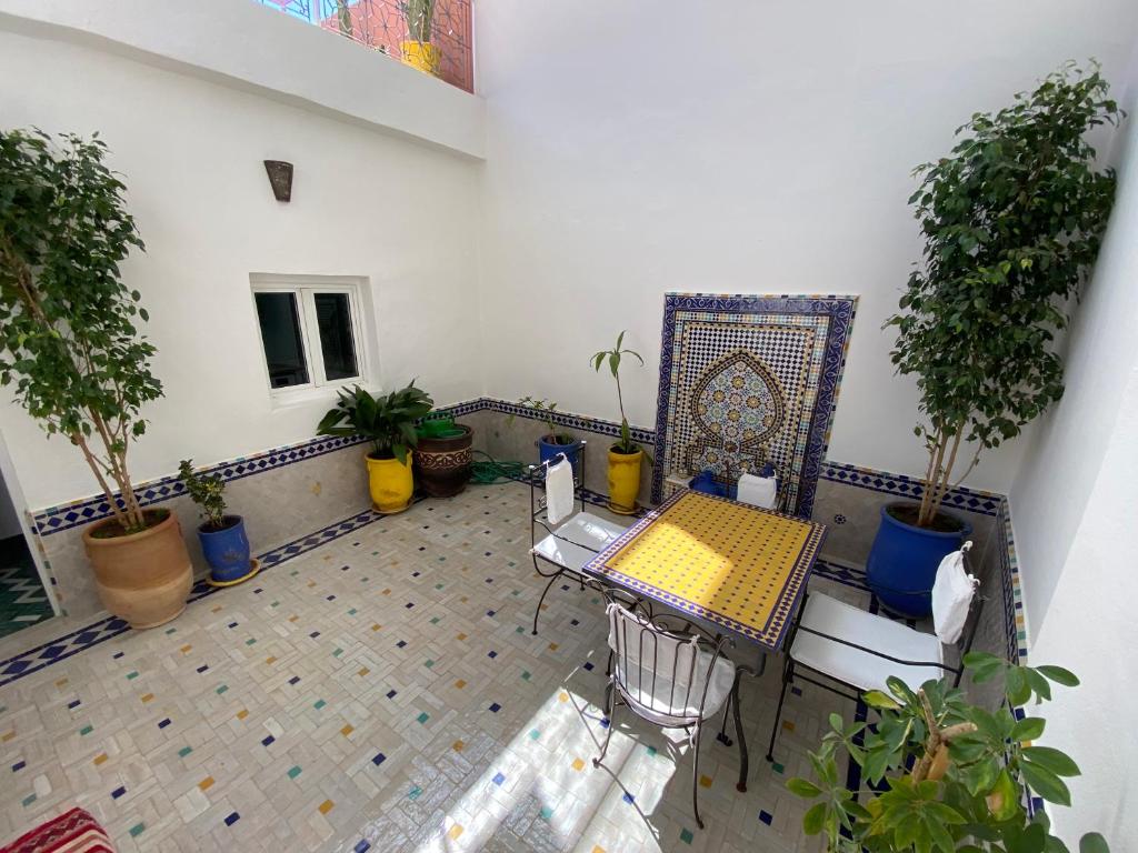 un patio con mesa, sillas y macetas en House Zitouna en Marrakech