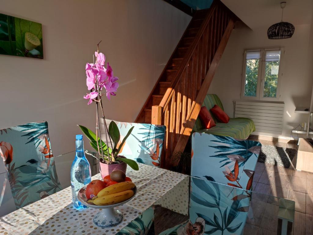 a table with a bowl of fruit and a flower on it at Logement calme et ensoleillé dans maison de ville in Villejuif