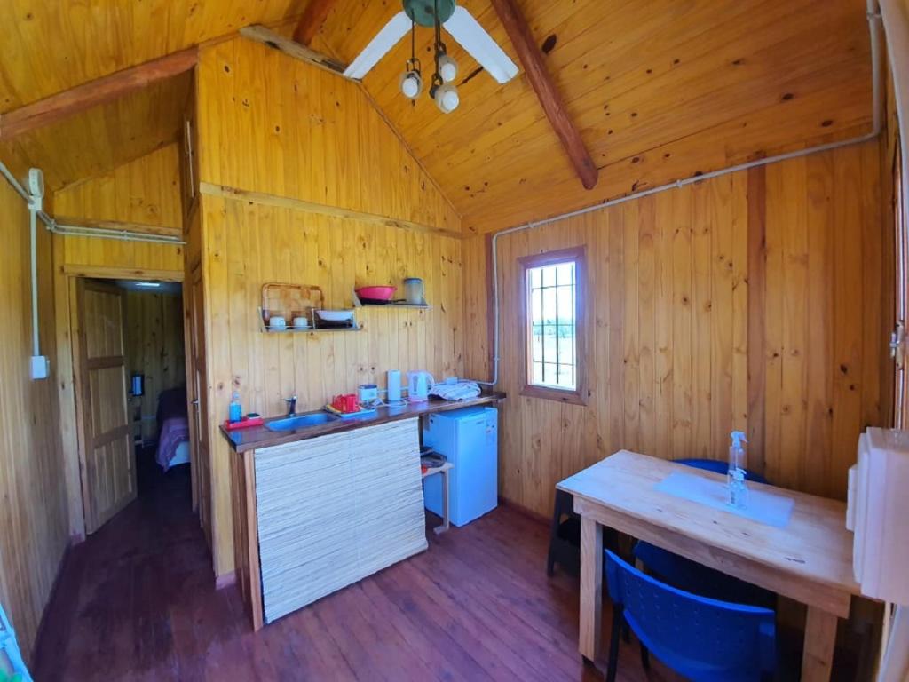 a kitchen in a wooden cabin with a wooden table at Chacra Mandala in Gualeguay
