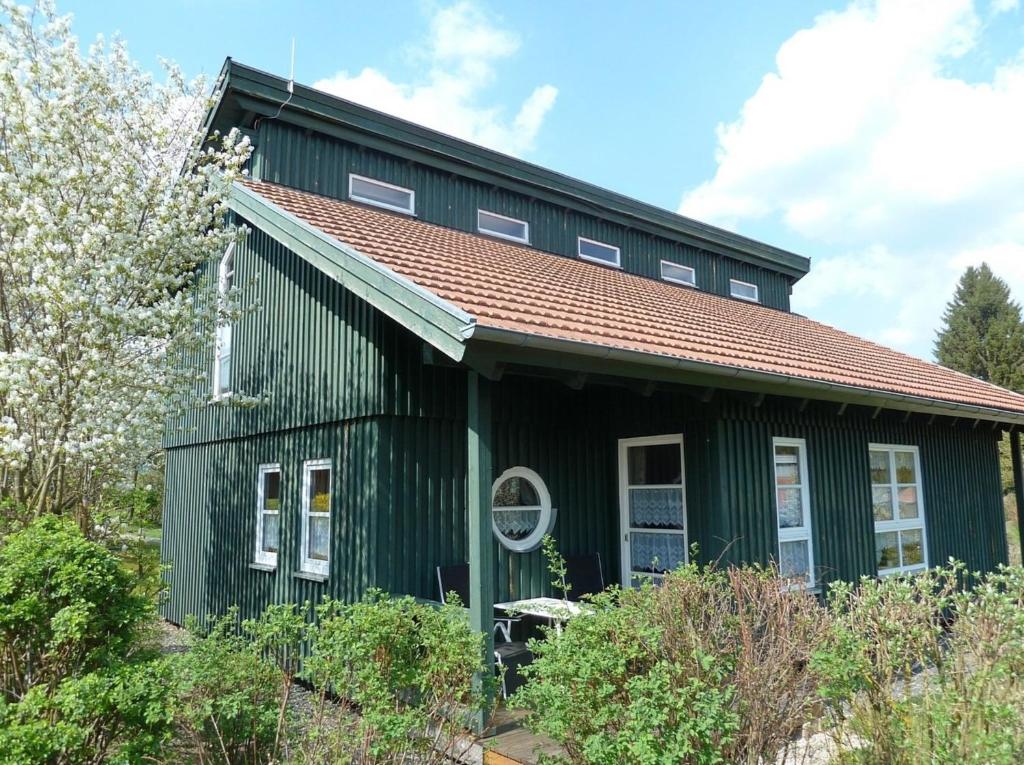 una casa verde con techo rojo en Ferienhaus Nr 18B1, Feriendorf Hagbügerl, Bayr Wald, en Waldmünchen