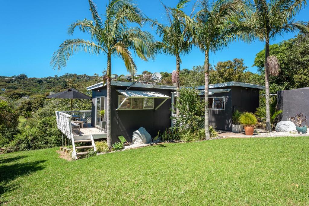 a house with palm trees in front of a yard at Four Palms Cottage - Onetangi Holiday Home in Onetangi
