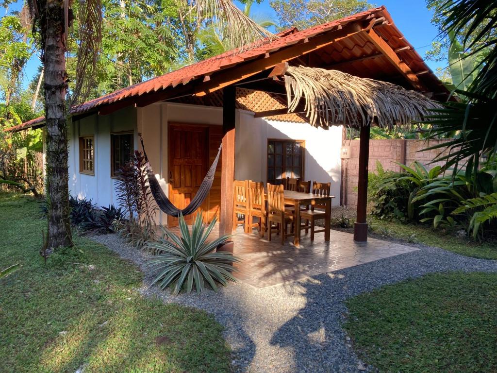 a house with a dining table and a thatched roof at Pura Vida Vegana in Cahuita