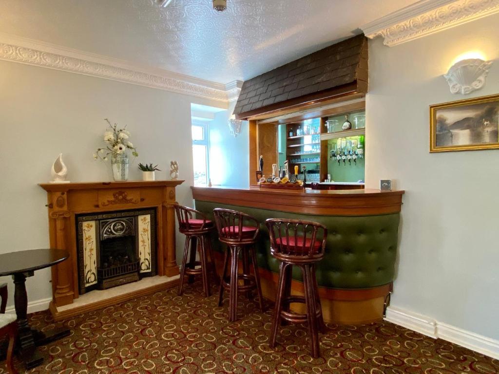 a bar with stools in a room with a fireplace at Bryn Noddfa in Morfa Nefyn