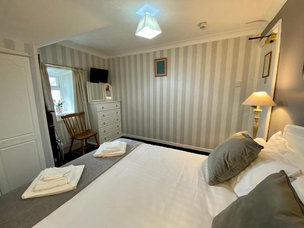 a bedroom with a large white bed and a chair at Bryn Noddfa in Morfa Nefyn