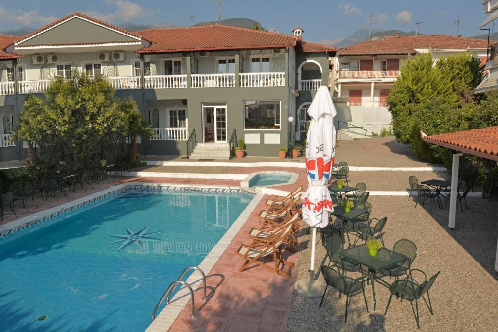 Olympus Hotel Villa Drosos في لتوخورو: مسبح وكراسي ومظلة أمام المبنى