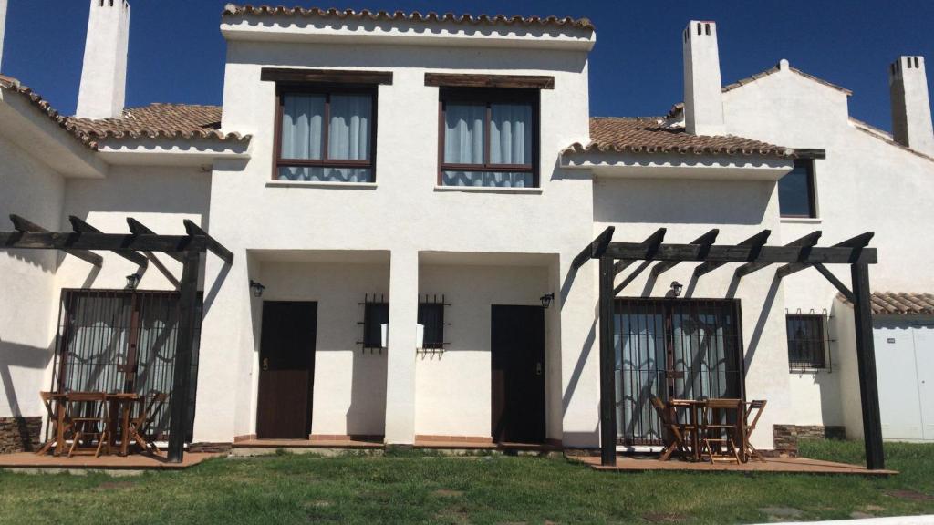 una casa blanca con sillas delante en Casa Rural El Olivar en Sevilla