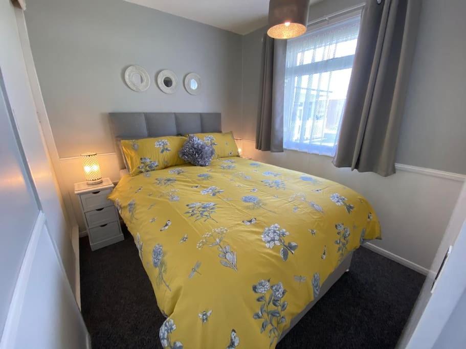 ein Schlafzimmer mit einem gelben Bett und einem Fenster in der Unterkunft East Coast Chalets 57 at California Sands in Scratby