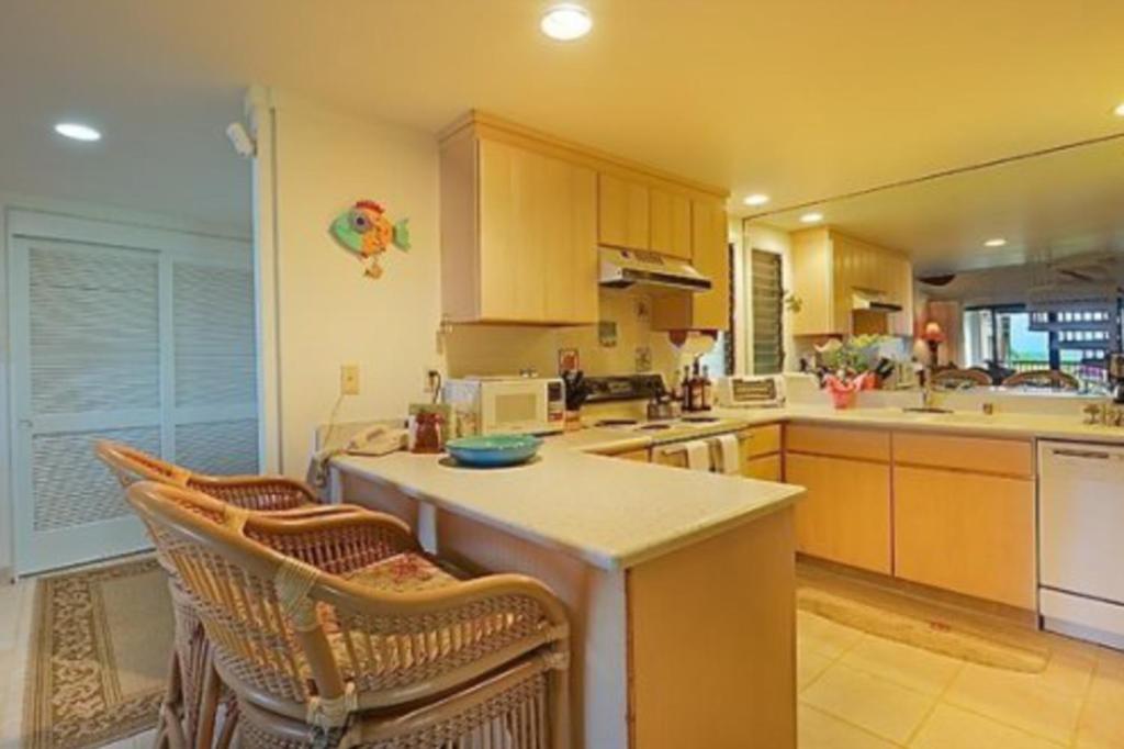 eine Küche mit einer Theke und ein paar Stühlen darin in der Unterkunft Hanalei Bay Resort 7302 in Princeville