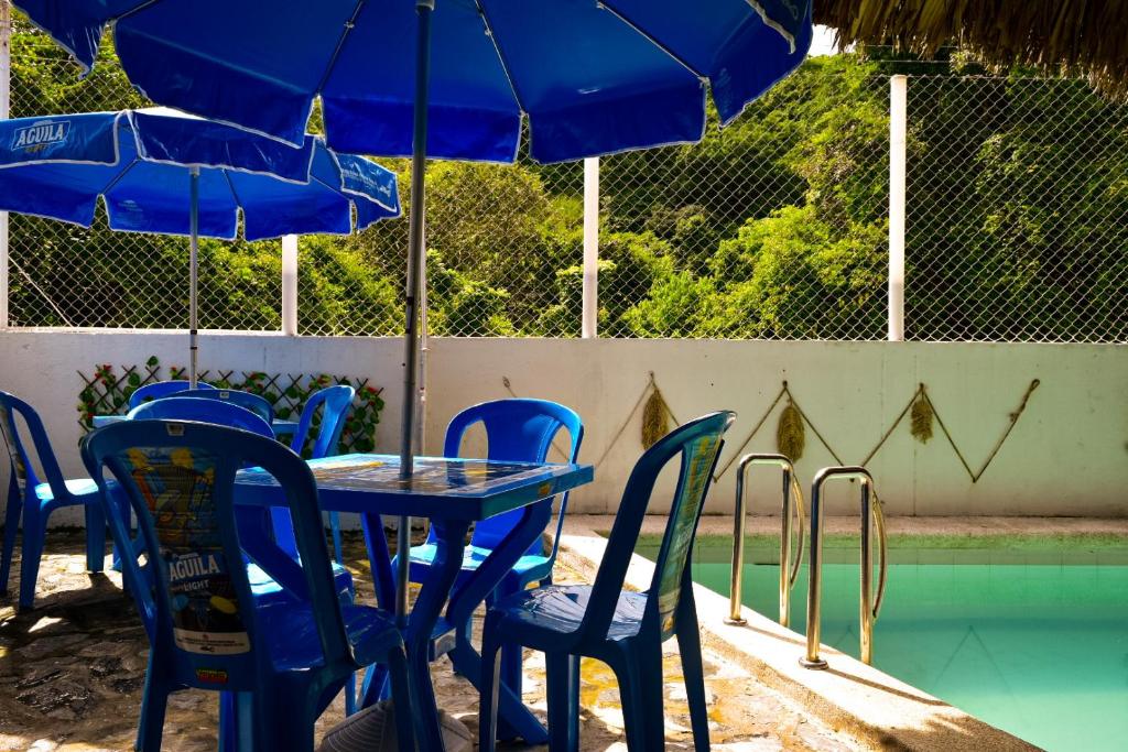 stół i krzesła z niebieskimi parasolami przy basenie w obiekcie Cabaña Ecoturistica Mirador del Bosque Tayrona w mieście Calabazo