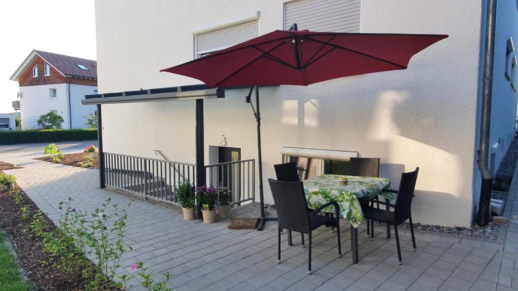 - une table et des chaises sous un parasol rouge sur la terrasse dans l'établissement MF Manuele Ficano - Ferienwohnungen am Bodensee - Fewo Stella, à Kressbronn am Bodensee