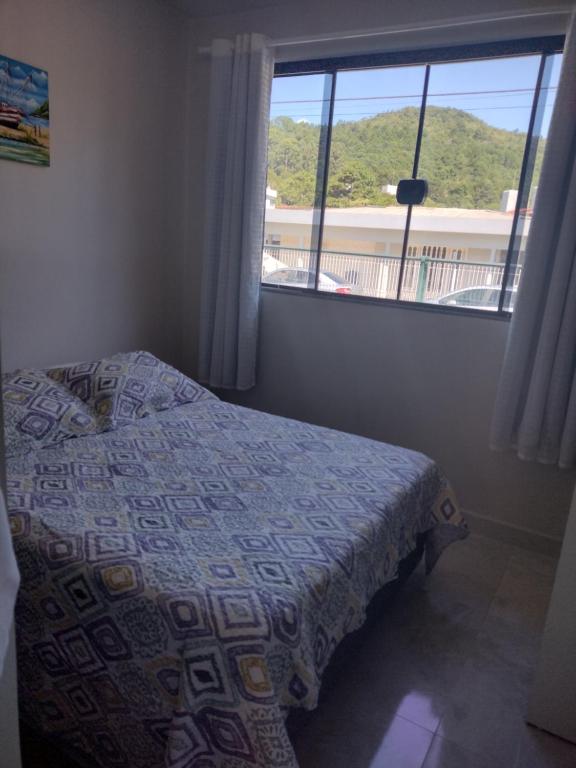 1 dormitorio con cama y ventana grande en Jurerê Residencial Acacia, en Florianópolis