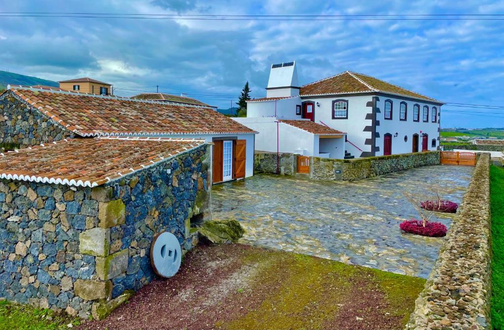 a house with a stone wall next to a building at Casa do Avô José Alves in Praia da Vitória