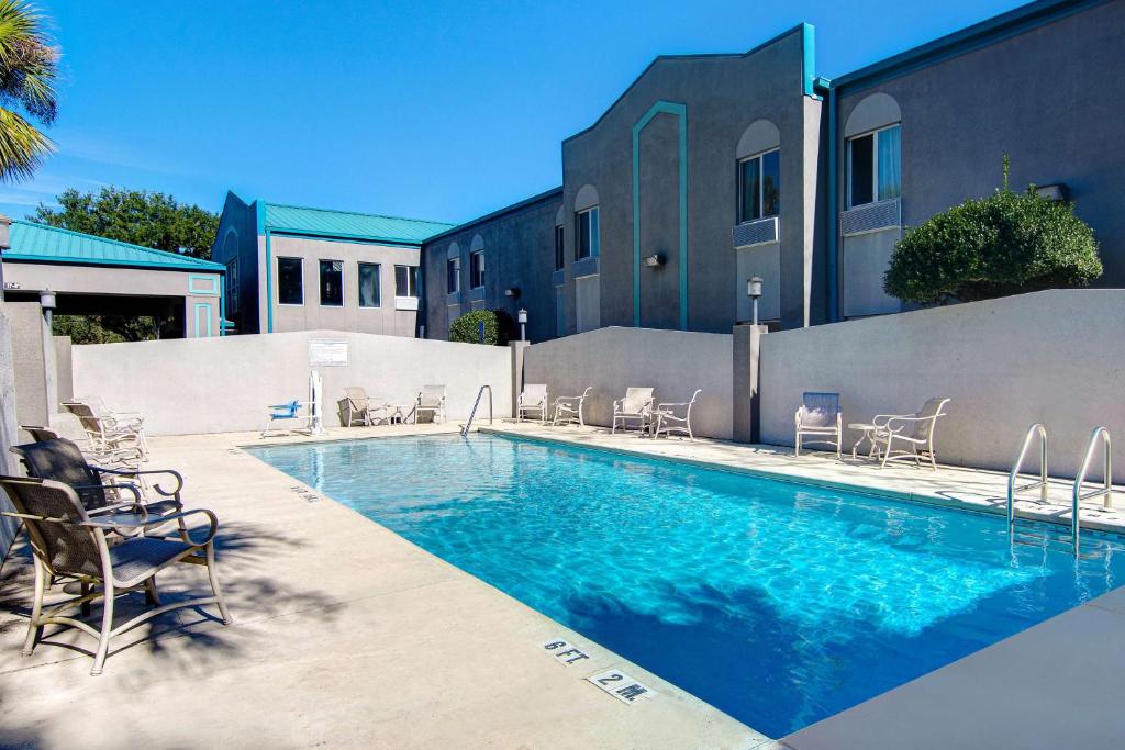 a swimming pool with chairs and a building at Studio 6 Pensacola, FL - West I-10 in Pensacola