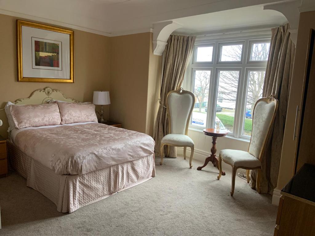 een slaapkamer met een bed en 2 stoelen en een raam bij Entire Seaside Home, Sleeps 8, All en-suite rooms in New Brighton