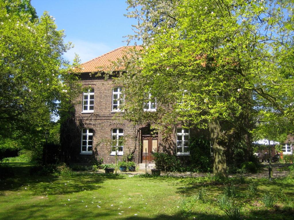 une vieille maison en briques avec un arbre dans la cour dans l'établissement Ferienwohnung Haumannshof, à Xanten