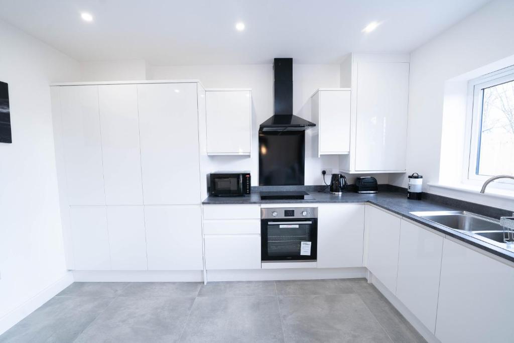 a white kitchen with a stove and a sink at Entire Modern Home with Private Parking for 6/8 Persons in Worksop