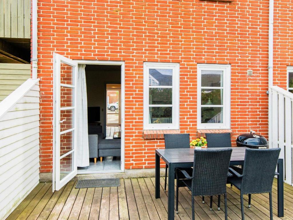 a patio with a table and chairs and a brick wall at 4 person holiday home in Rømø-By Traum in Sønderby