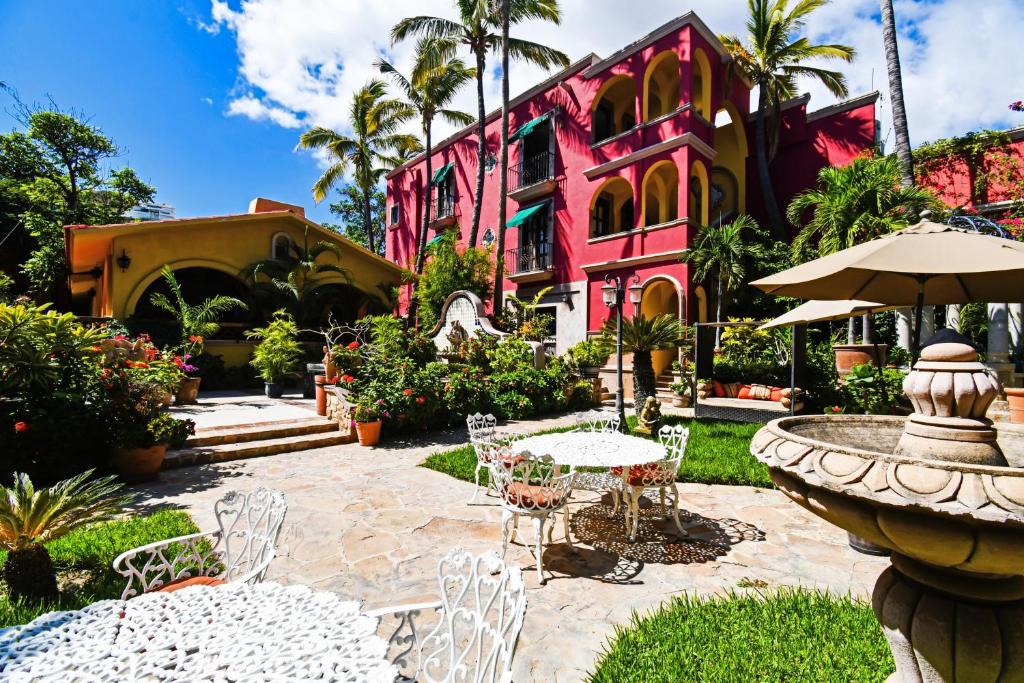 una casa rosa con una fuente, mesas y sillas en Collection O Casa Bella Hotel Boutique, Cabo San Lucas en Cabo San Lucas