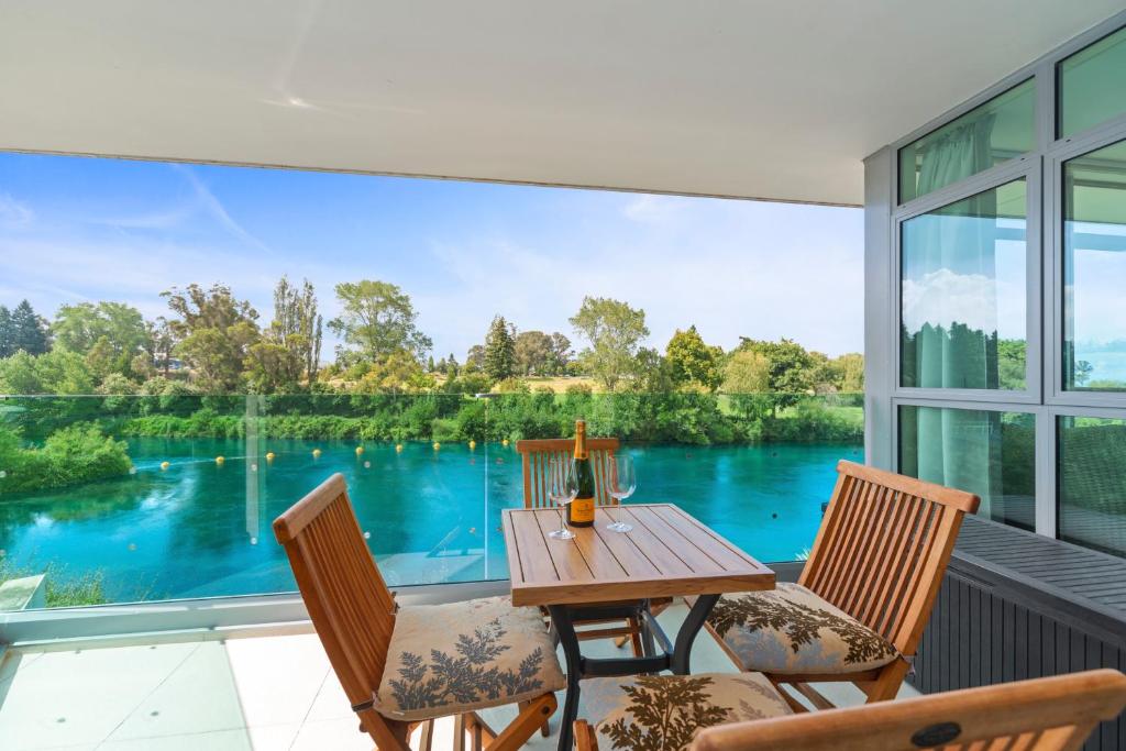 a table and chairs on a balcony with a view of a lake at Two Views Taupo Apartment in Taupo