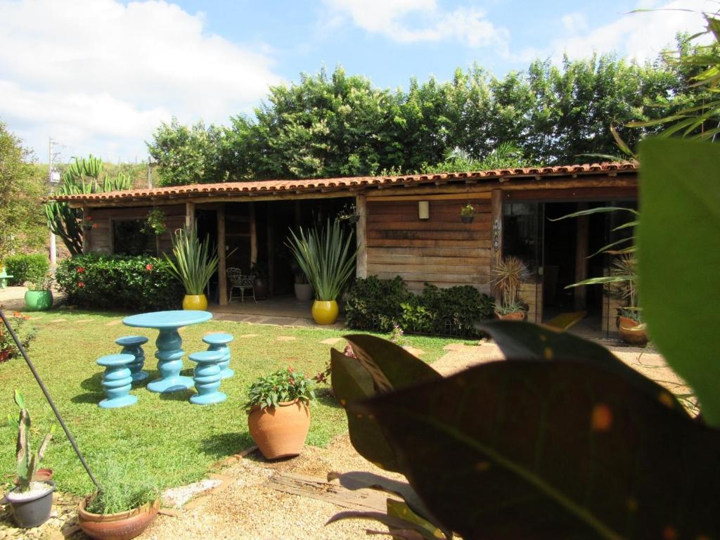 a yard with a table and some plants and a house at La Villa Chalés Garden in Serra Negra