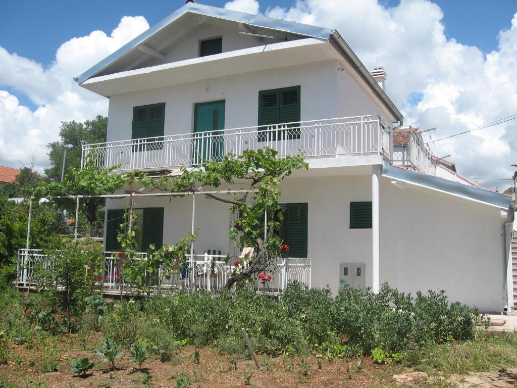 Casa blanca con balcón y árboles en Apartments Zora, en Pirovac