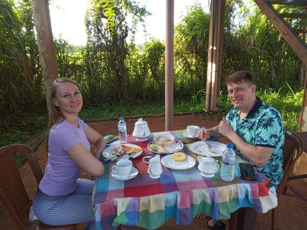 Ein Mann und eine Frau sitzen an einem Tisch mit Essen in der Unterkunft Sigiriya Paddy Field Hut in Sigiriya