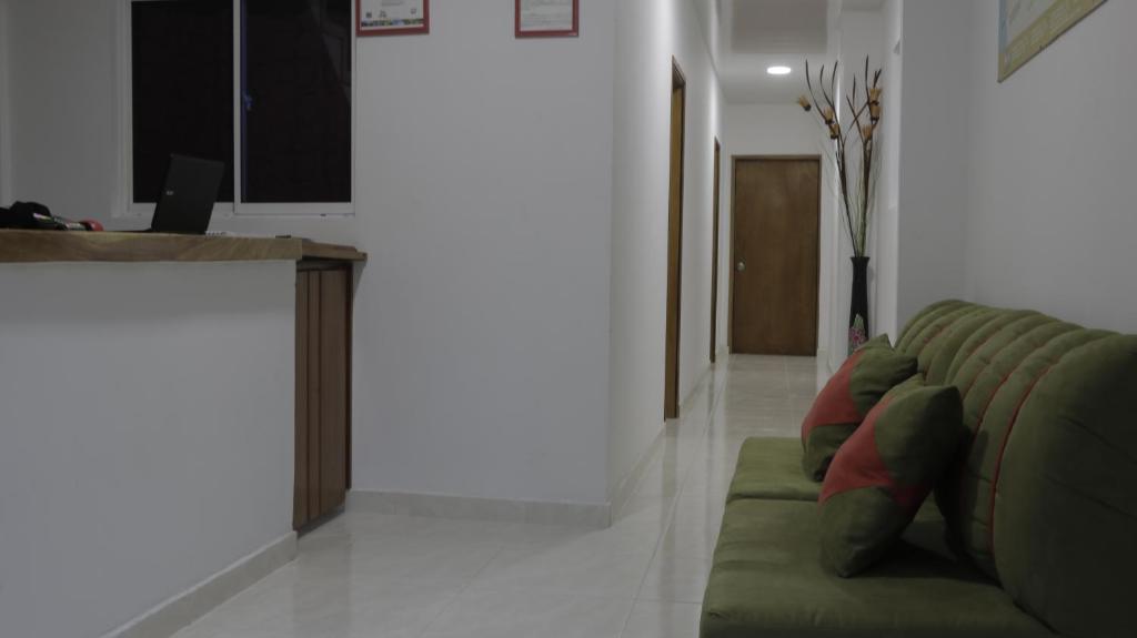 a living room with a green couch and a counter at Puerto Caribe Hostal in Guachaca