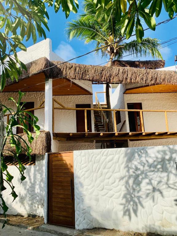 a house with a thatched roof and a garage at Casa Palmeira in Pipa