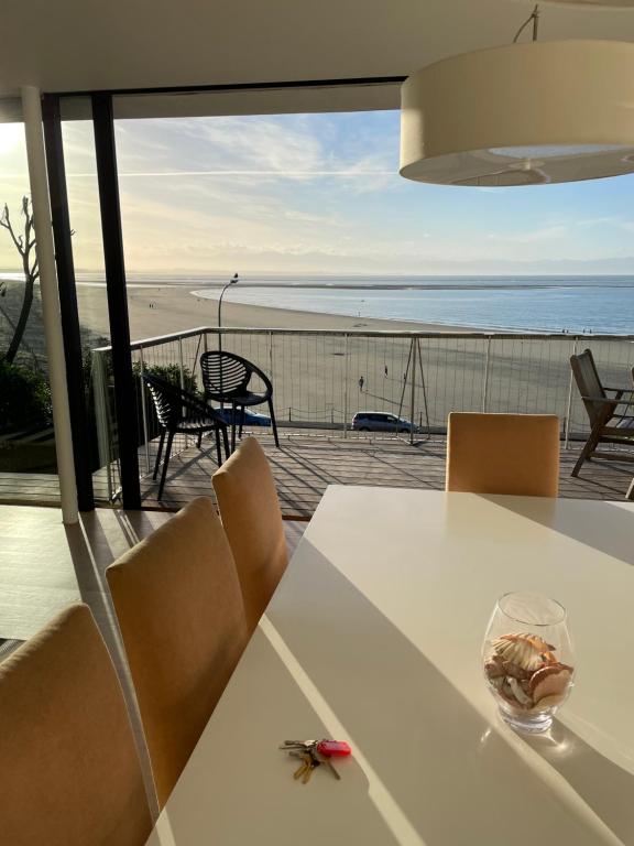einen weißen Tisch und Stühle mit Blick auf den Strand in der Unterkunft LUXURIOUS WATERFRONT Home in Nelson