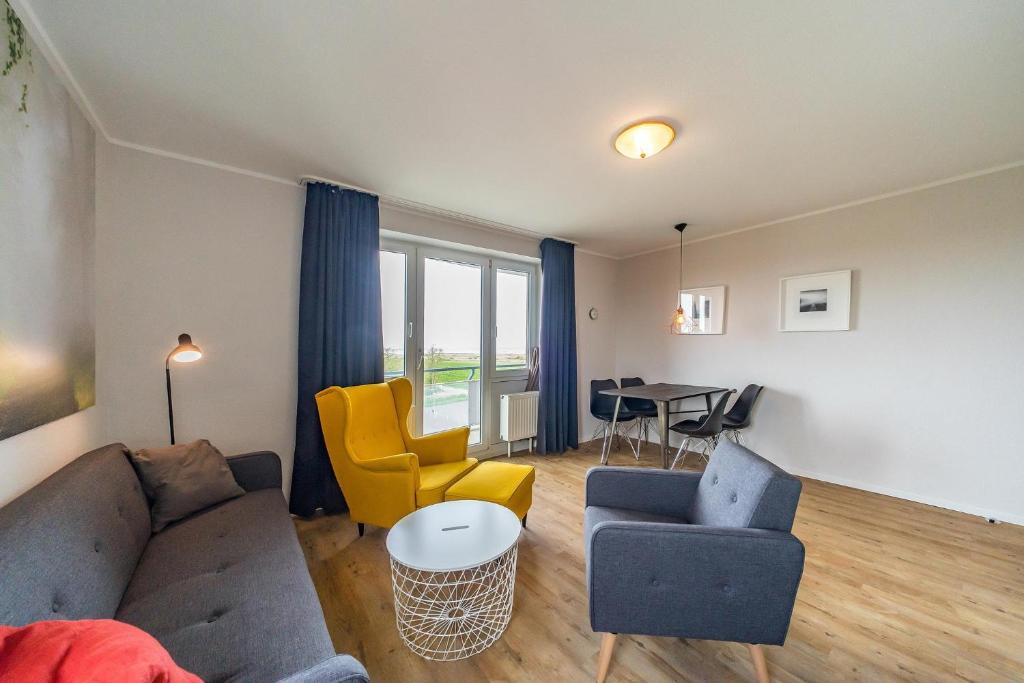 ein Wohnzimmer mit einer Couch und Stühlen und einem Tisch in der Unterkunft Hus Inselkieker Hus Inselkieker 425 in Schillig