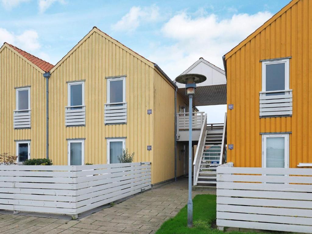 eine Reihe gelber Häuser mit einer Treppe davor in der Unterkunft 6 person holiday home in Rudk bing in Rudkøbing