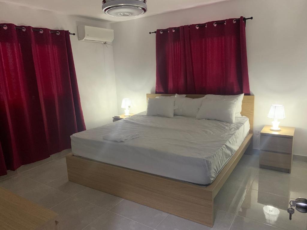 1 dormitorio con 1 cama grande y cortinas rojas en 3bed Apartment con Terraza y Picsina privada en Santo Domingo