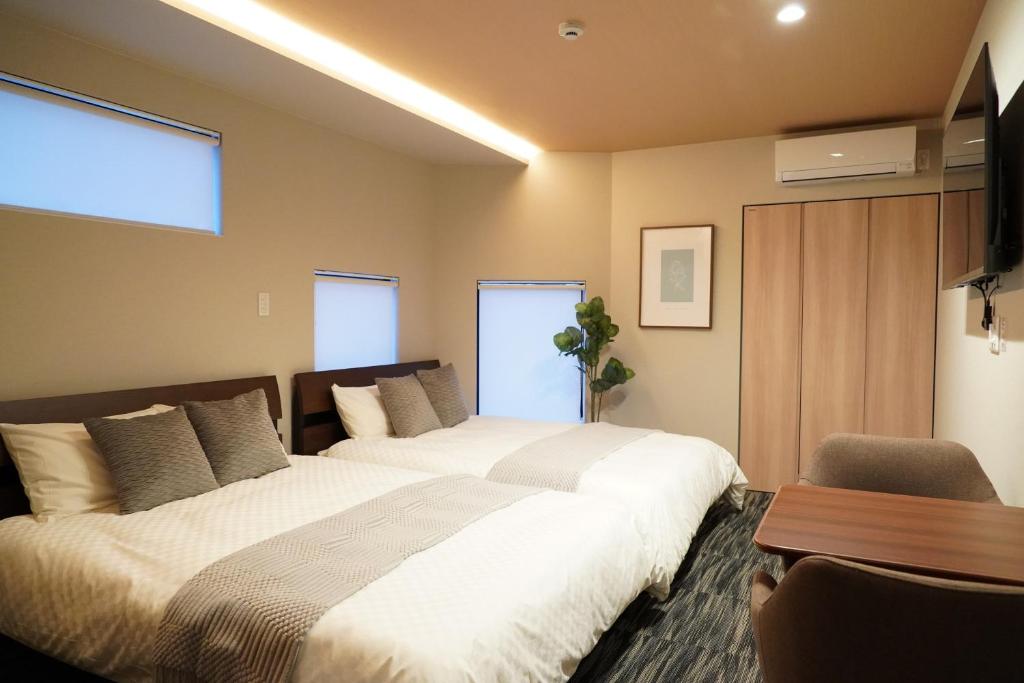 a bedroom with two beds and a table at Liaison Court Nishikujo Universal Bay in Osaka