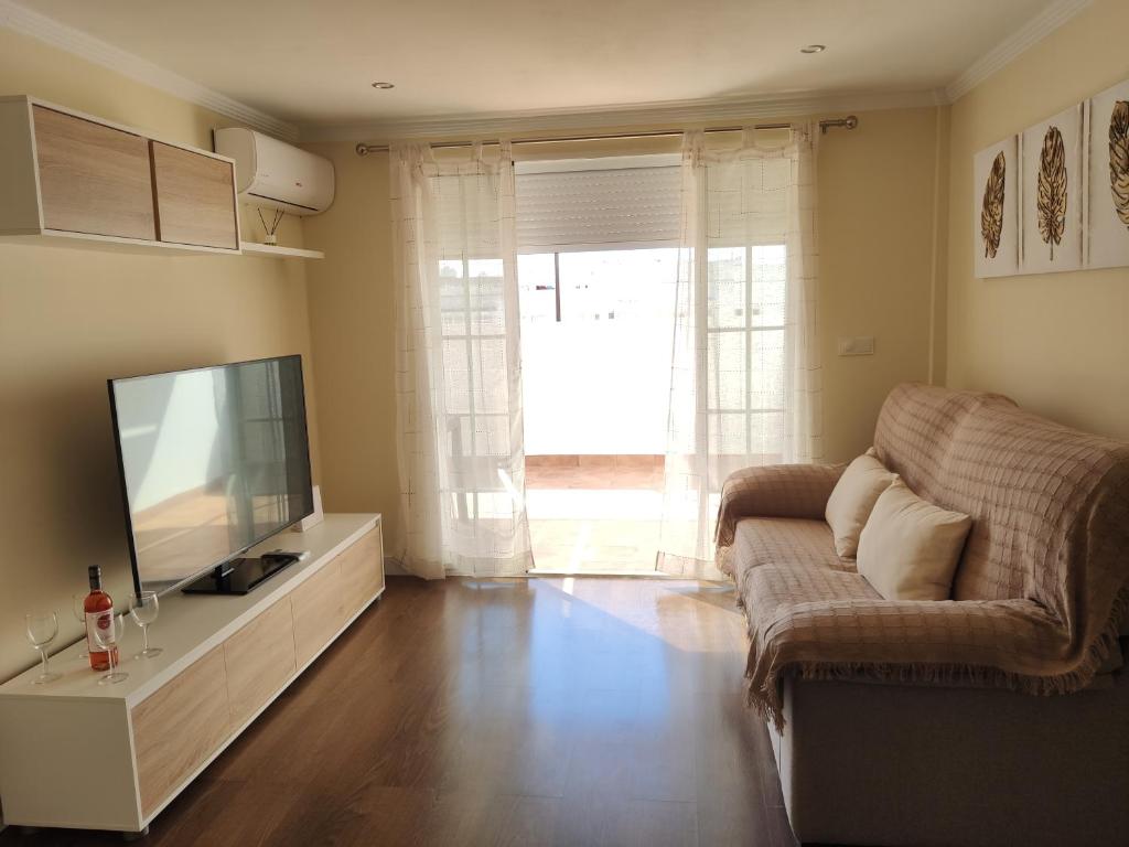 sala de estar con TV y sofá en Luz y Mar Huelva-Ático, en Huelva