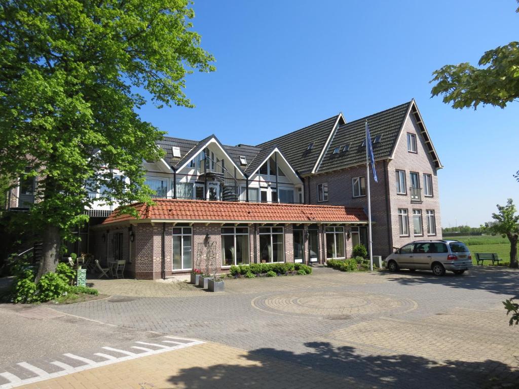 a building with a car parked in front of it at Hotel Orion in Kaag