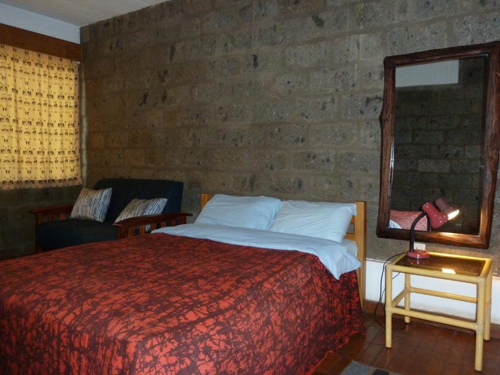 a bedroom with a bed and a brick wall at Villa Rock Stop Falls Gigiri in Nairobi