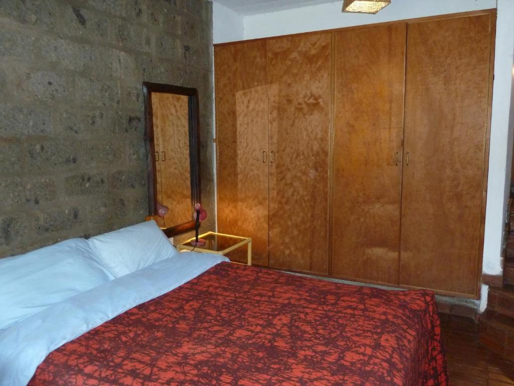 a bedroom with a large bed and wooden cabinets at Villa Rock Stop Falls Gigiri in Nairobi