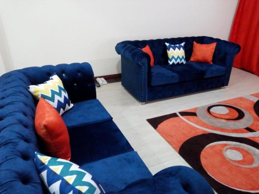 un soggiorno con 2 divani blu e un tappeto di Lux Suites Royal Family Apartment Nyali a Mombasa