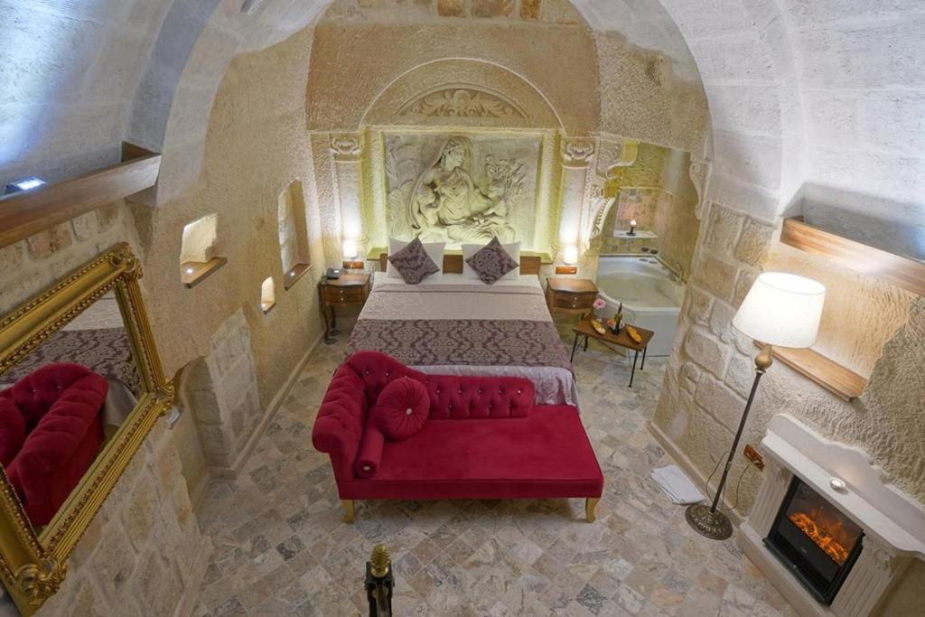 a bedroom with a bed and a couch and a fireplace at Arte Cave Hotel in Urgup