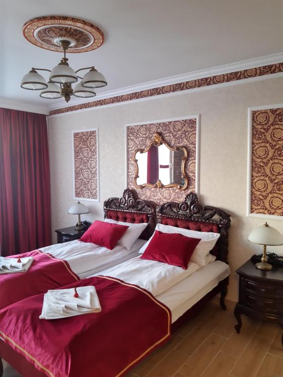 a bedroom with two beds with red sheets and a mirror at Apartament Jasiu in Ustka