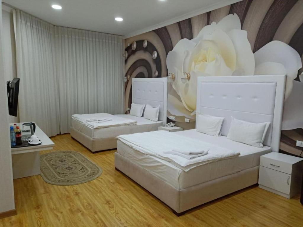 タシュケントにあるQueens 2 hotelのベッドルーム1室(ベッド2台付)と花の壁画が備わります。