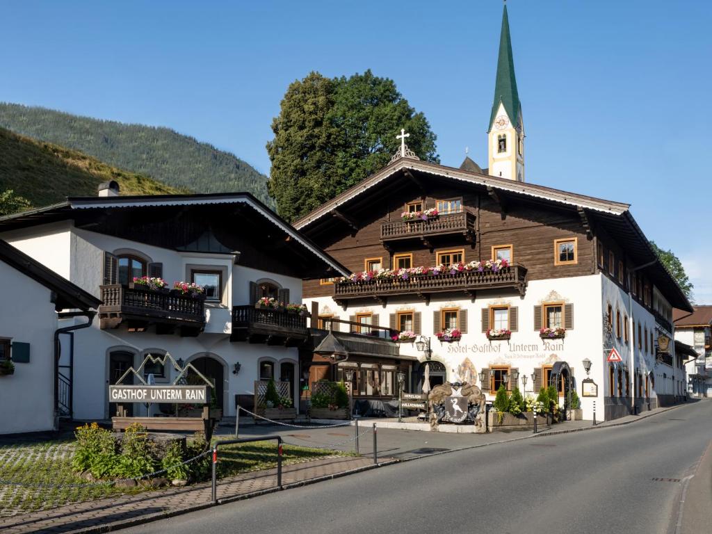 a building on the side of a road with a church at Alpen Glück Hotel Unterm Rain garni in Kirchberg in Tirol