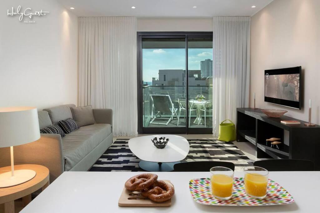 a living room with a couch and two glasses of orange juice at Dashing 1BR in White city by HolyGuest in Tel Aviv