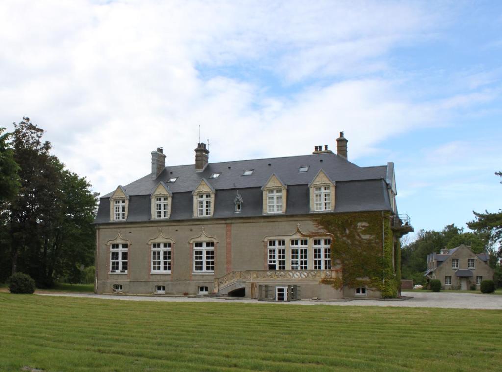 a large house with a large grass field in front of it at Manoir de la Dune in Quend